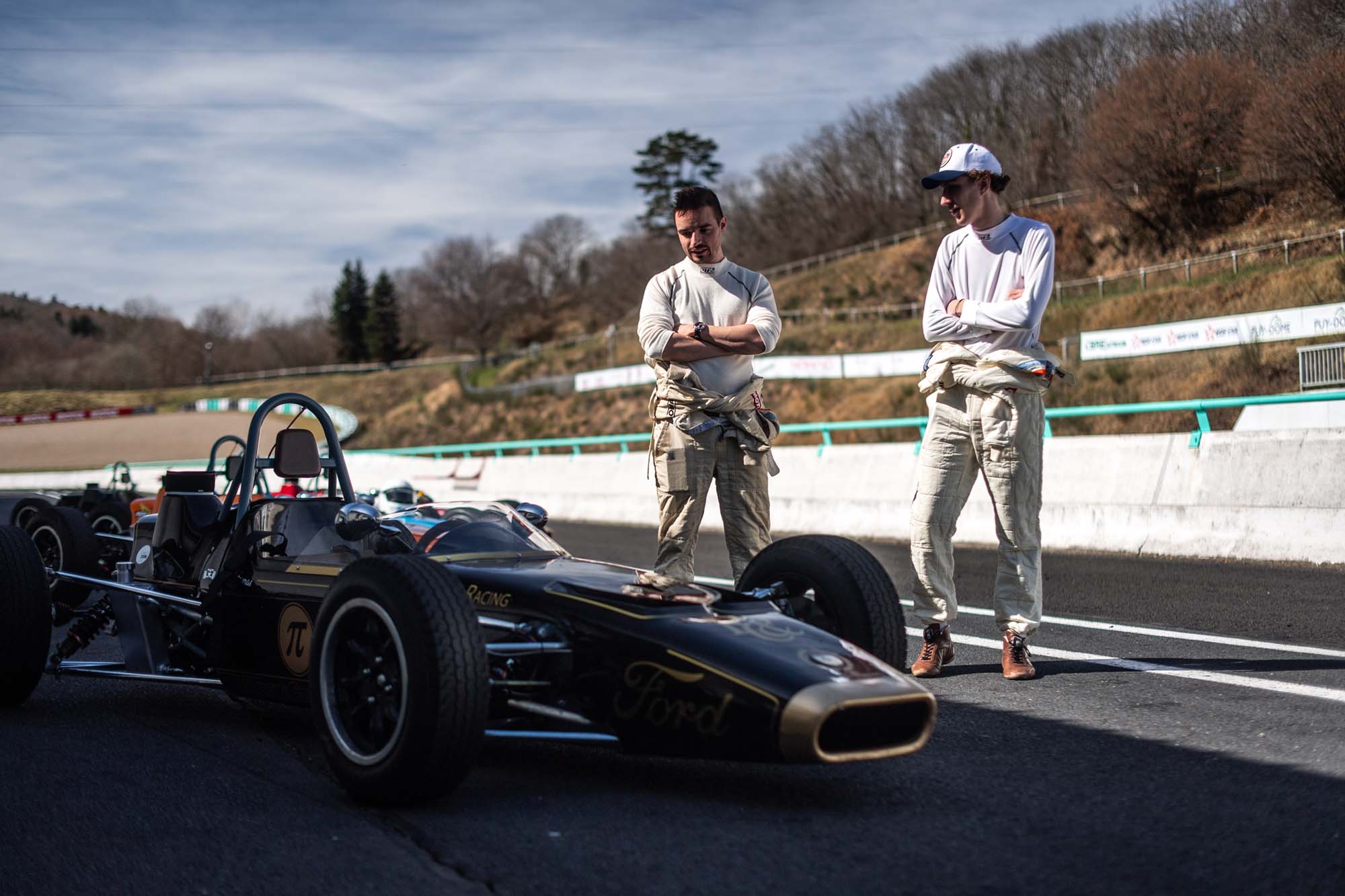 two men standing next to a race car